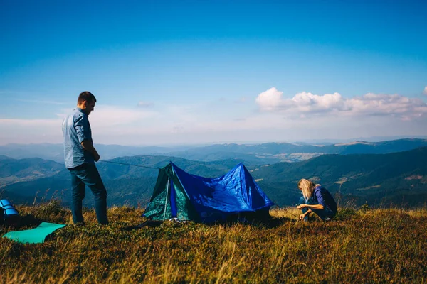 Young couple setting up tent in mountains. Hiking and camping. — 스톡 사진