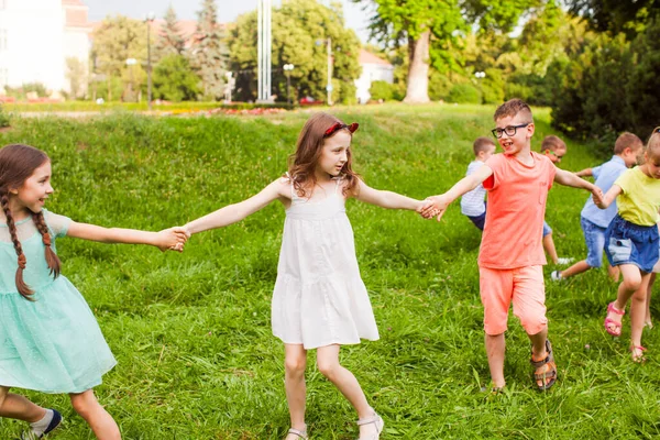 Happy children holding hands and playing outdoors game — Stock Photo, Image