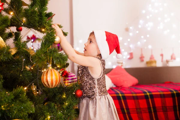 Happy child girl decorating Christmas tree at home — ストック写真