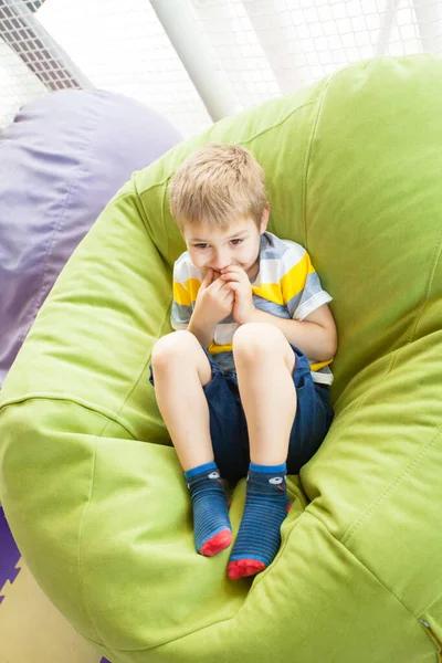 Szczęśliwe dziecko odpoczywające na nowoczesnej torbie fasoli na placu zabaw — Zdjęcie stockowe