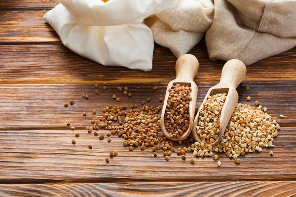 Green and fried buckwheat grains in the wooden scoops — Stock Photo, Image