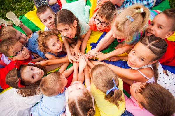 Top view kids in circle laying on colorful cloth — Stock Photo, Image