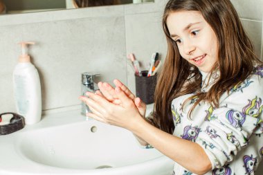 Kız ellerini banyoda yıkıyor.