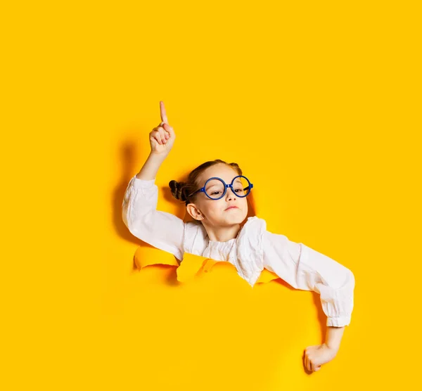 Menina olhando inteligente olhando para fora de rasgado na parede — Fotografia de Stock