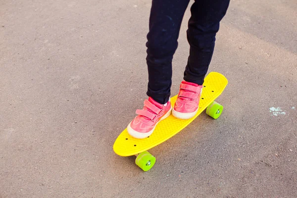 Skateboarder meninas pernas de pé em um skate — Fotografia de Stock