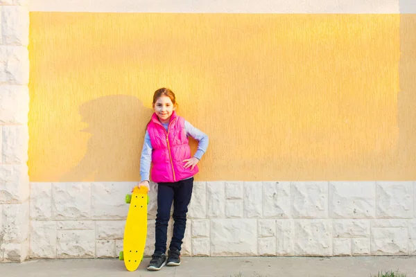 Jovem hipster preteen posando perto da parede com skate — Fotografia de Stock