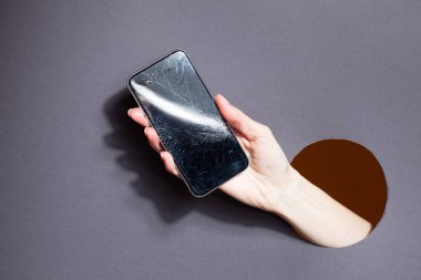 Duvardaki bir delikten telefonu tutan kadın.