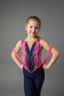 Gri arka planda spor giysili güzel bir jimnastikçi kız..