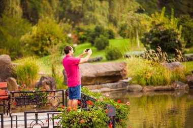 Parktaki telefonuna fotoğraf çeken adam.