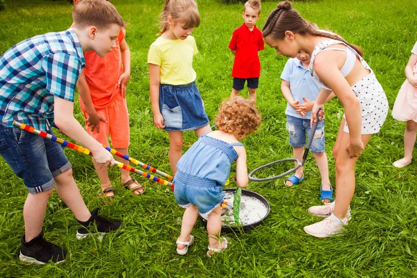 Grupo de niños pequeños que aprenden a hacer grandes burbujas de jabón — Foto de Stock