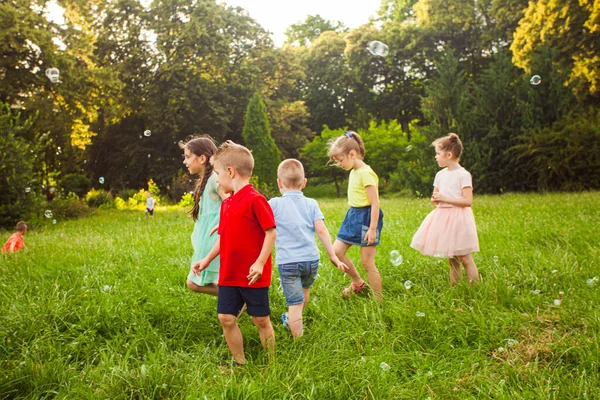 Los niños pequeños se relajan en el jardín después de las clases. — Foto de Stock