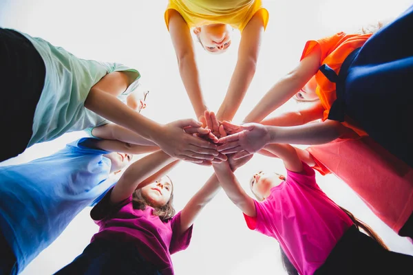 Niños poniendo sus manos juntas en el interior en camisetas de arco iris —  Fotos de Stock