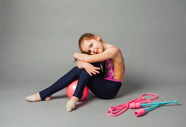 Flicka gymnast poserar med spets och rep på grå bakgrund. — Stockfoto