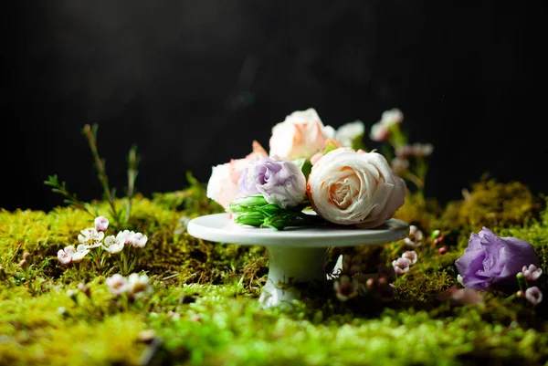 Rosas em um suporte branco cercado por musgo verde — Fotografia de Stock