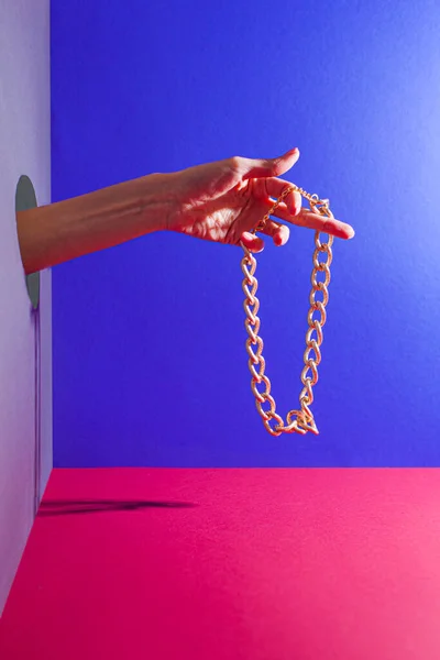 Mano de mujer con cadena dorada que sobresale de la pared — Foto de Stock