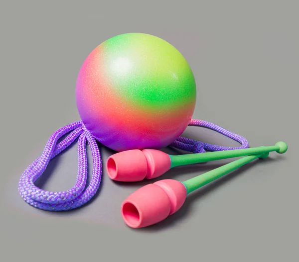 Rhythmic gymnastics equipment on grey background. Green ball, mace and rope for gymnastics. — Stock Photo, Image