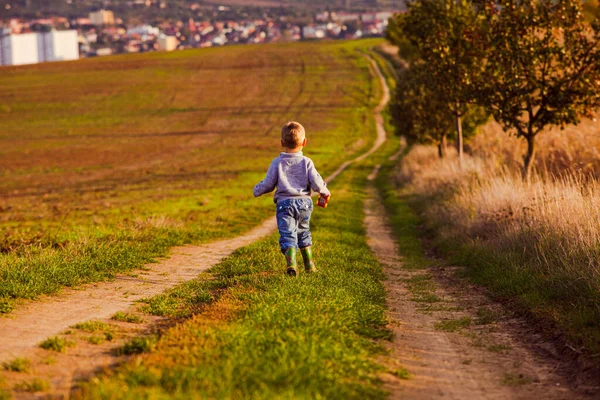 Маленький хлопчик йде по сільській дорозі — стокове фото