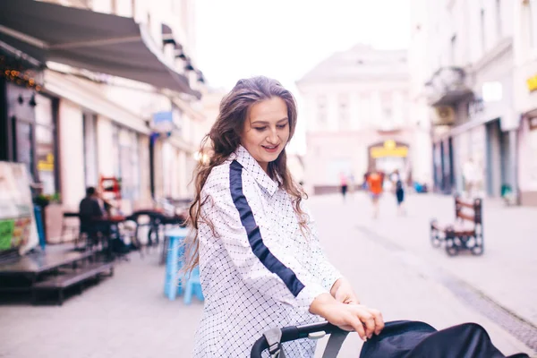 Feliz mamá está caminando con cochecito en el centro de la ciudad europea — Foto de Stock