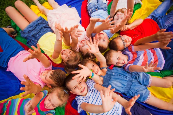 Little friends on a floor raising hands up — Stock Photo, Image