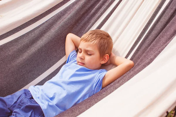 Förskolekillen ligger i hängmatta på sommardagen — Stockfoto