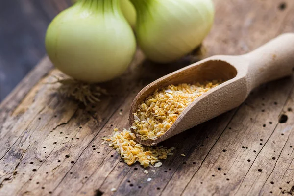 Dried up onions in spice scoop on old wooden table — Stock Photo, Image