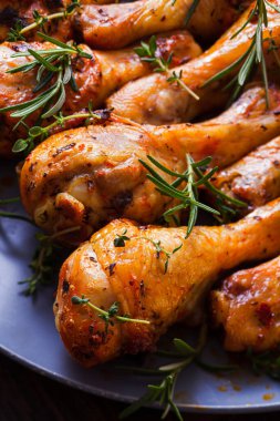 Koyu gri tabakta taze pişmiş tavuk bacağı.