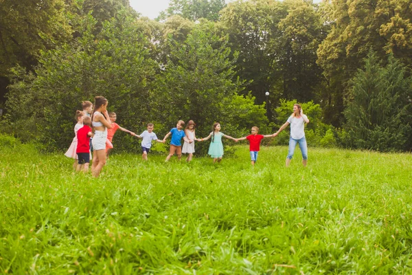 As crianças e um professor se divertem no parque — Fotografia de Stock