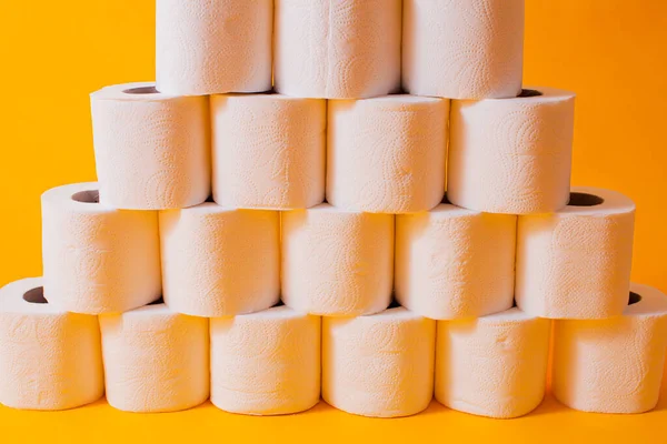 Toilet paper rolls as a wall background pattern over yellow — Stock Photo, Image