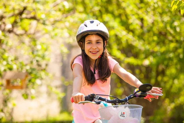 戴着头盔的微笑女孩骑着粉红的女孩自行车 — 图库照片