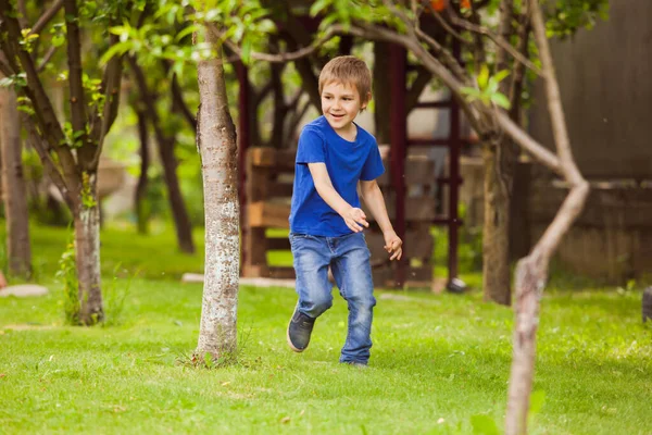 Das Kind läuft auf dem Rasen zwischen einem Baum — Stockfoto