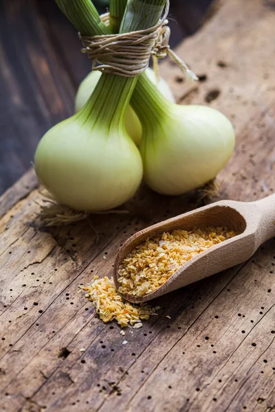 Especia de cebolla en cucharada de madera sobre una superficie de madera vieja —  Fotos de Stock