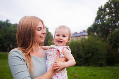 Gülümseyen sarışın anne ve kızı parkta dinleniyorlar.