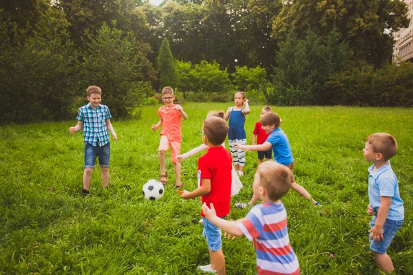 Boys and girls are playing soccer in the summer park — Stock Photo, Image