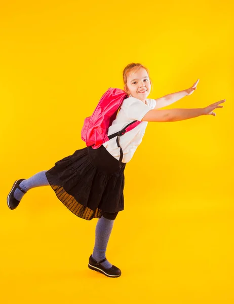 Школьница с рюкзаком во время прыжка на желтом — стоковое фото