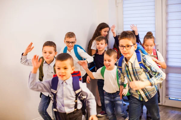 Skolbarnen springer nerför skolkorridoren och skyndar sig hem. — Stockfoto