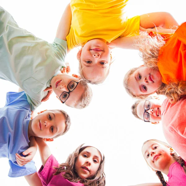 Circle of smiling kids embracing together in t-shirts — Stock Photo, Image