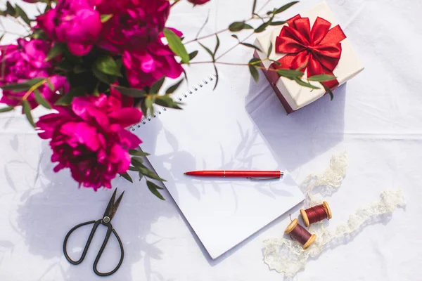 Livro nota aberta com caneta e flores em vaso — Fotografia de Stock