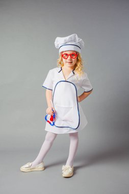 Tıp üniformalı küçük kız insanları tedavi etmeye hazırlanıyor.