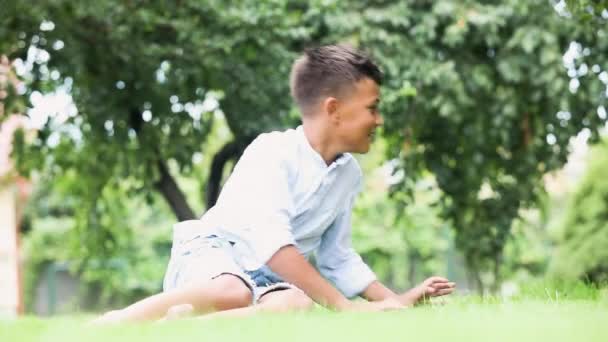 Vrolijke jongen besteedt tijd buiten op groen gazon — Stockvideo