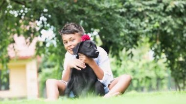 Yaz çimlerinde köpeğini kucaklayan bir çocuk.