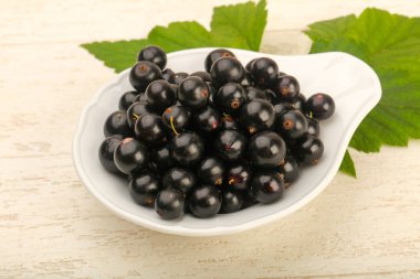 Olgun siyah kuş üzümü ile yaprak kase