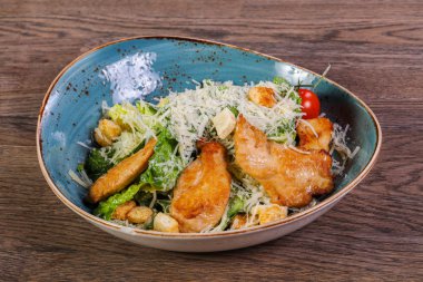 Sezar salatası ahşap masa üzerinde tavuk ve parmesan peyniri ile