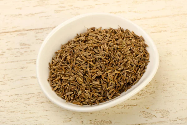 Kimyon tohumları yığın içinde kase ahşap arka plan üzerinde