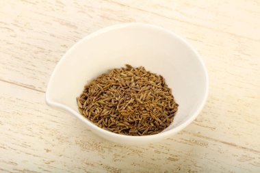 Kimyon tohumları yığın içinde kase ahşap arka plan üzerinde