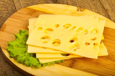 Ahşap masanın üzerine dilimlenmiş peynir salata yaprakları