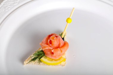 Beyaz tabakta somonlu sandviç.