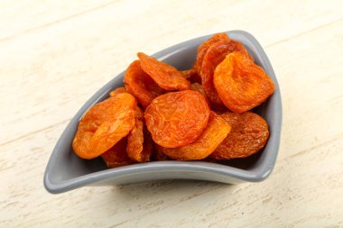 Kuru Kayısı yığın içinde kase ahşap arka plan üzerinde