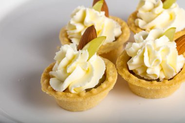 Krema, üzüm ve badem ile Tartlets beyaz tabakta görmek yakın