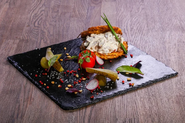 Potato cakes with meat served tomatoes on black stone plate