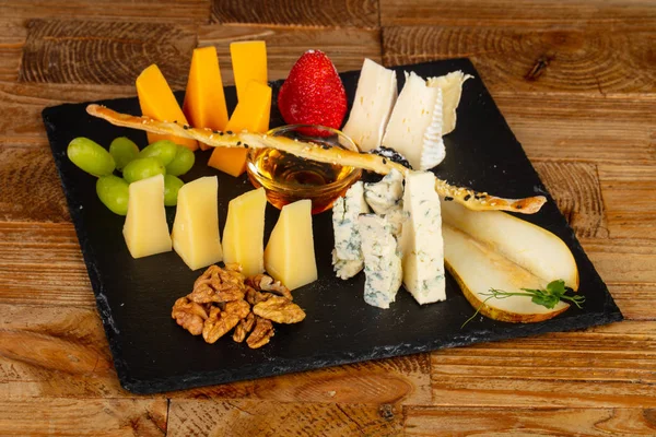 Peynir, çilek ve ahşap masa üzerinde fındık ile snack yer